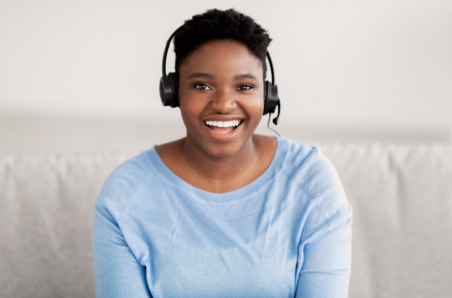 Black woman sitting, looking to camera wearing headset Physical therapy receptionist happily assisting calls