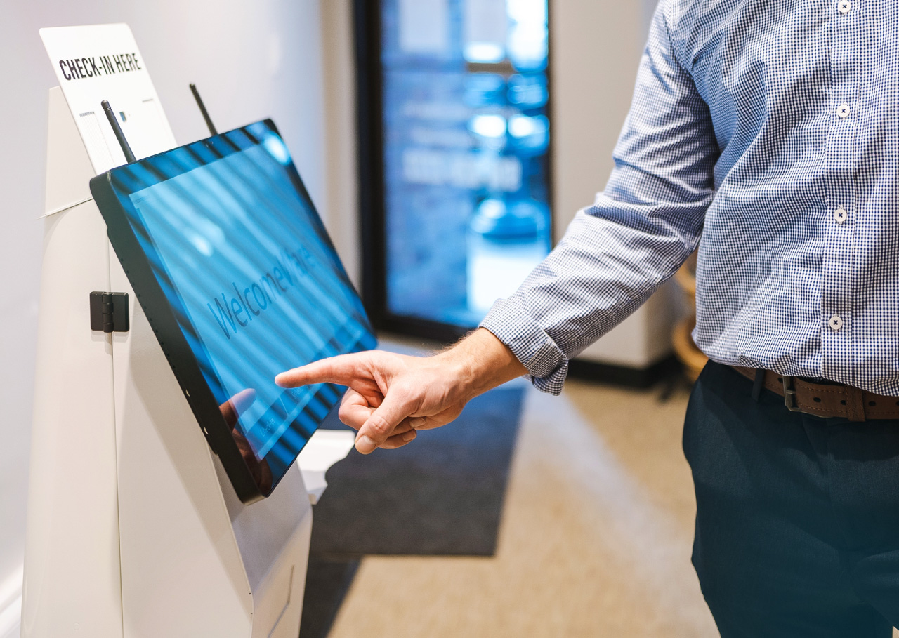 woman facing the virtual front-desk receptionist kiosk machine