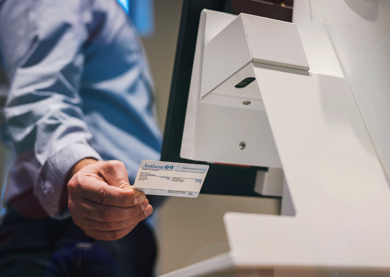 woman scanning the id on the virtual front-desk receptionist kiosk machine