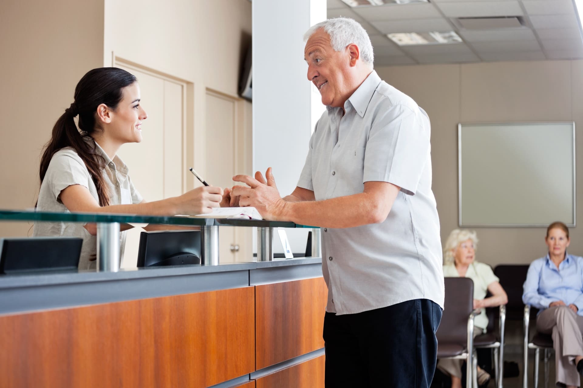 Receptionist facilitating patient experience with happy patient